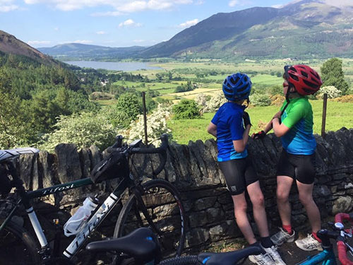 Two students chatting in their bicycle gear while overlooking beautiful green scenery